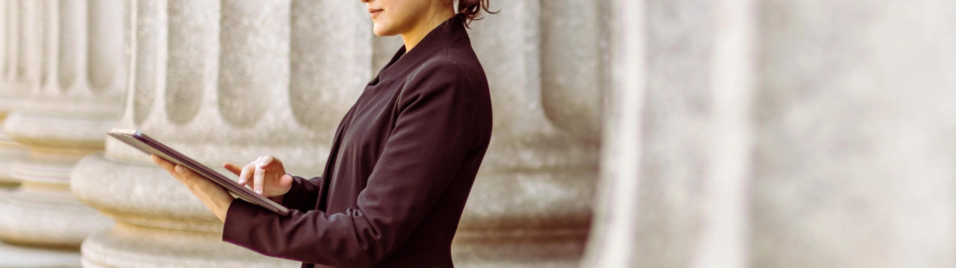 Businesswoman standing outside bank working on a tablet