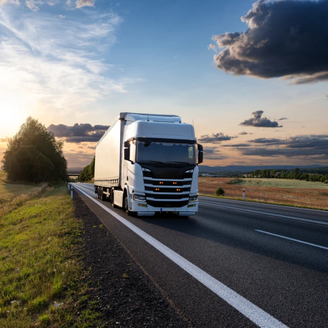 truck driving sunset on road by greenery
